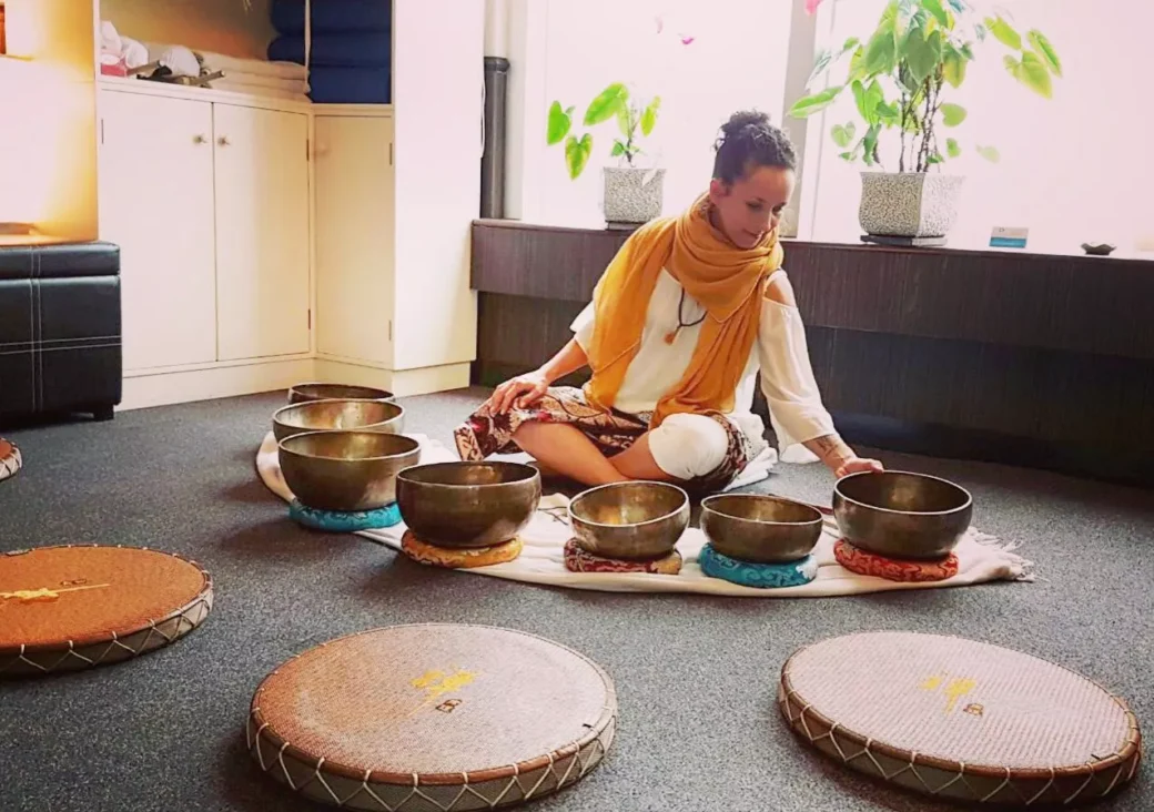 Woman meditating with Tibetan singing bowls during a sound healing session