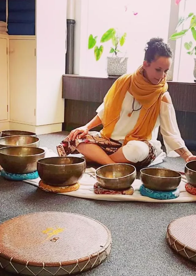 Woman meditating with Tibetan singing bowls during a sound healing session